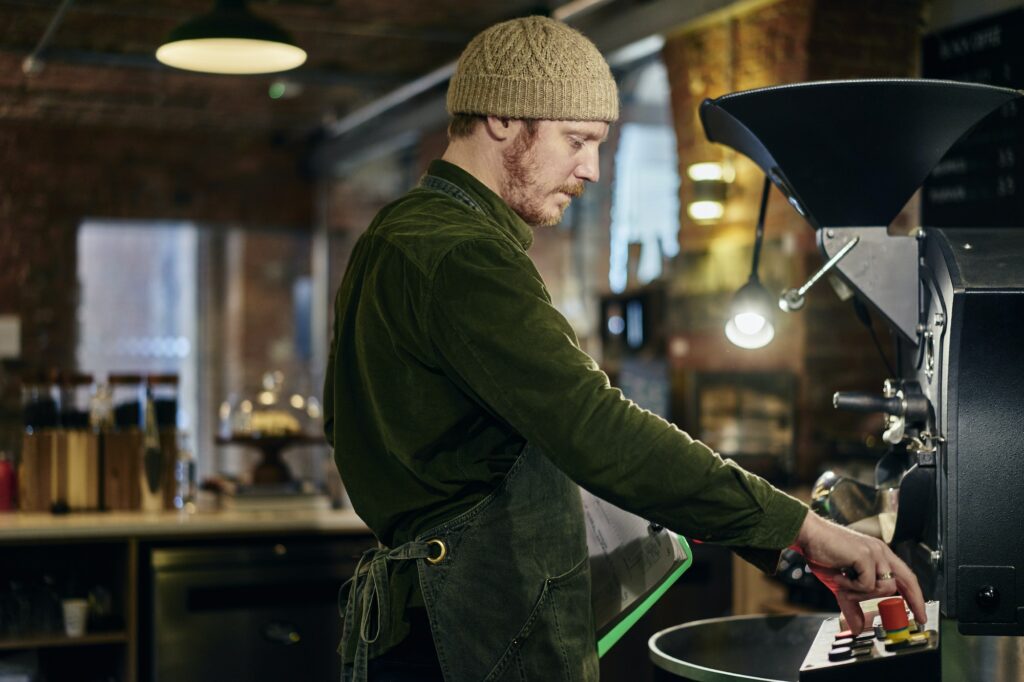 Male coffee shop owner using coffee roaster