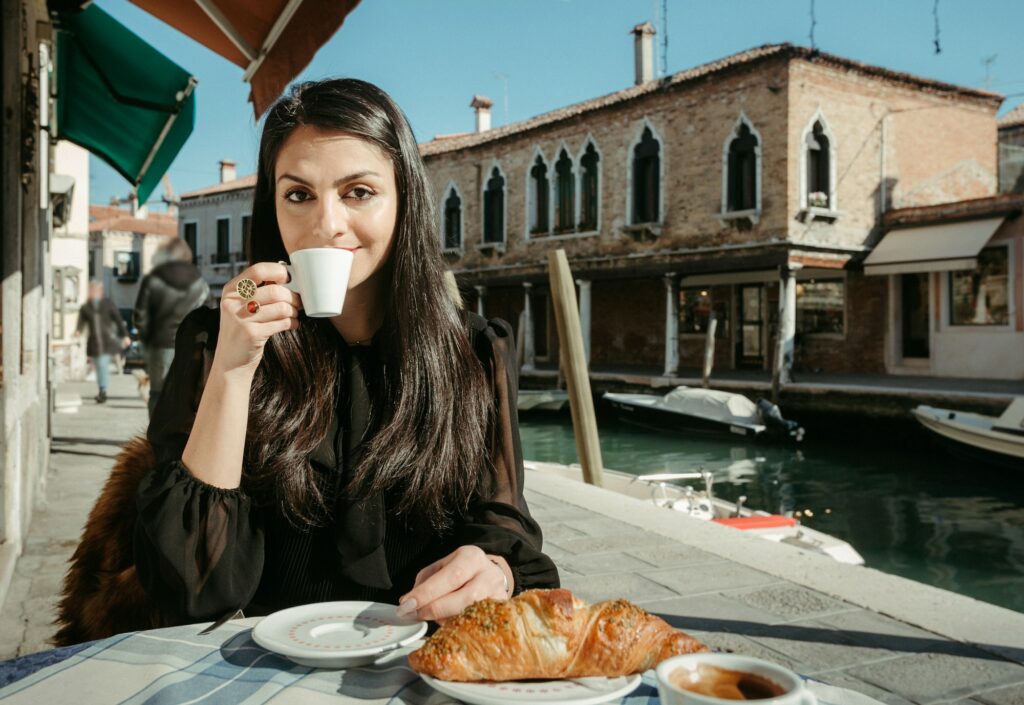 Smiling young woman drinking coffee in a Street Bar in Venice, Italy.