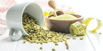 Unroasted green coffee beans on white table.