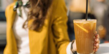 Young woman drinking iced coffee with tonic and lemon on summer terrace.