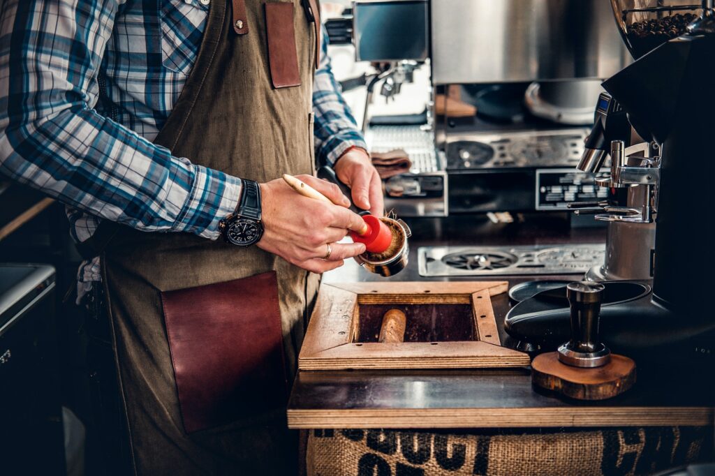 A man cleans coffee machine with a tassel.