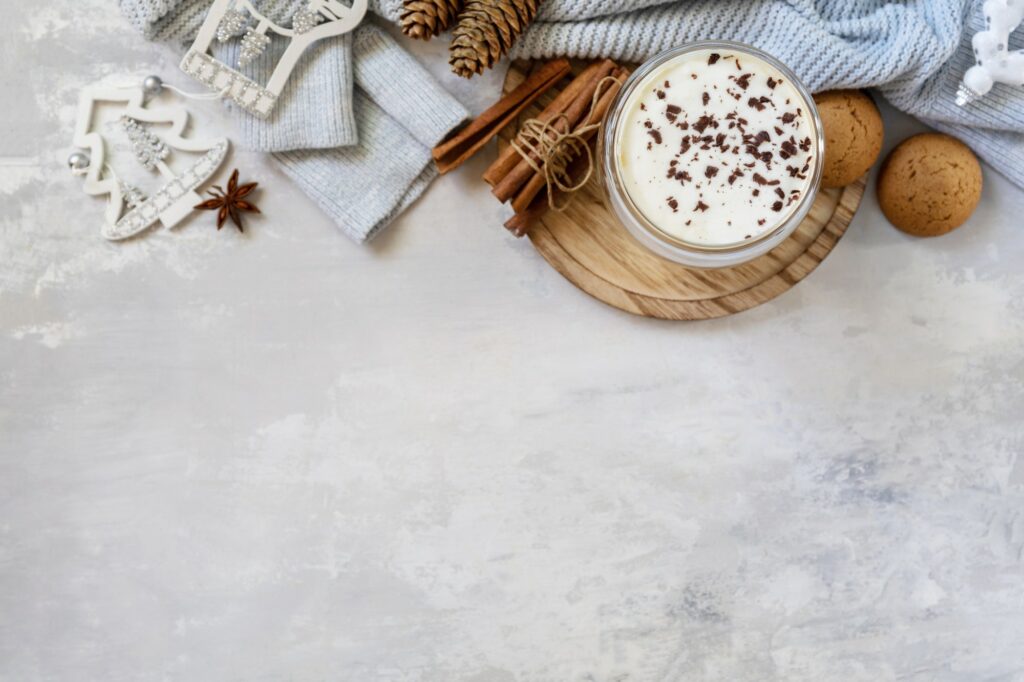 Latte spice coffee, warm pullover and Christmas decor on gray background.