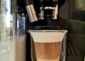 Kaffeemaschinen Fresh latte made in automatic coffee machine in glass with double heat-resistant walls.