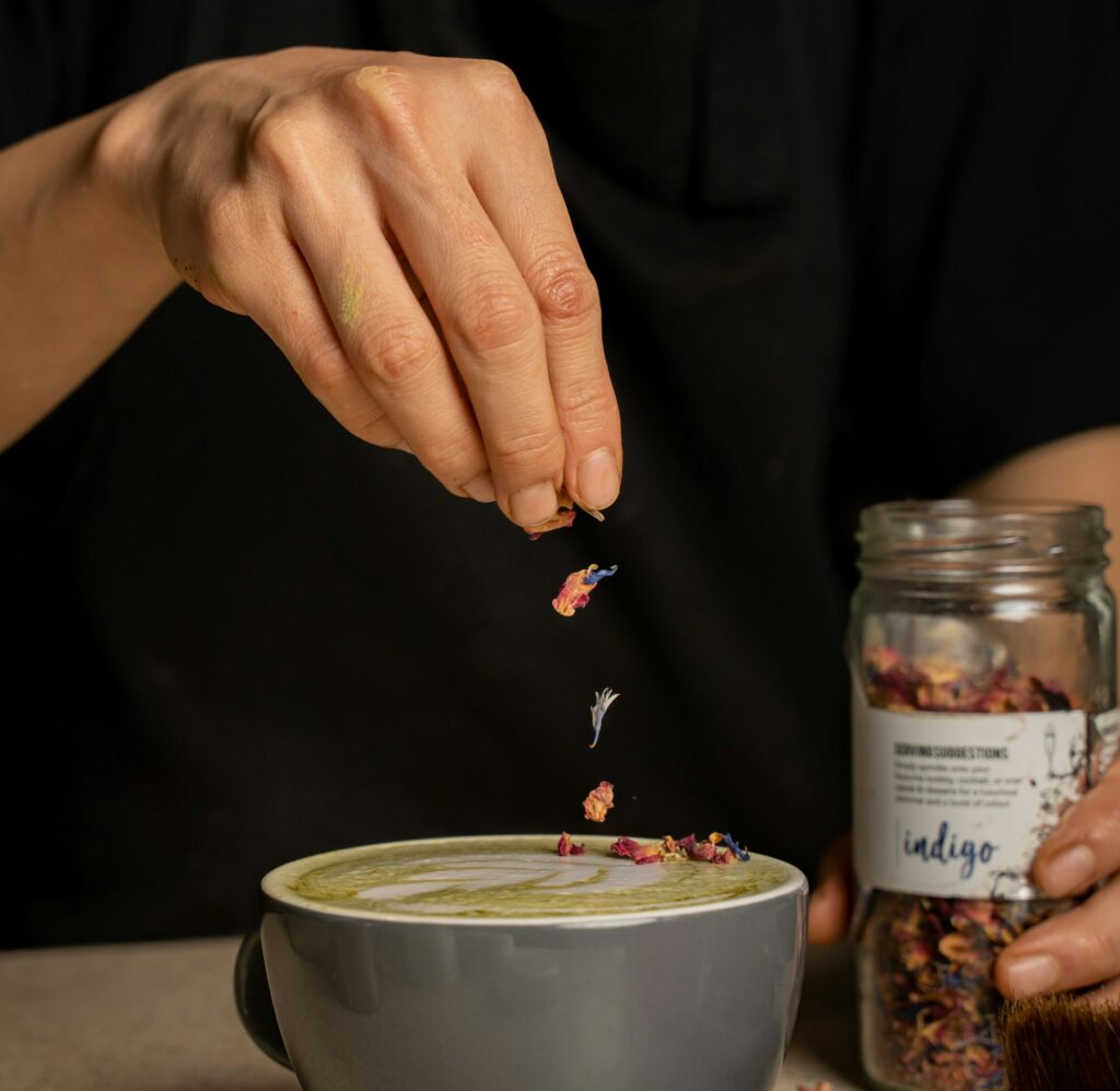 Barista putting edible dried flowers on a cup of coffee latte