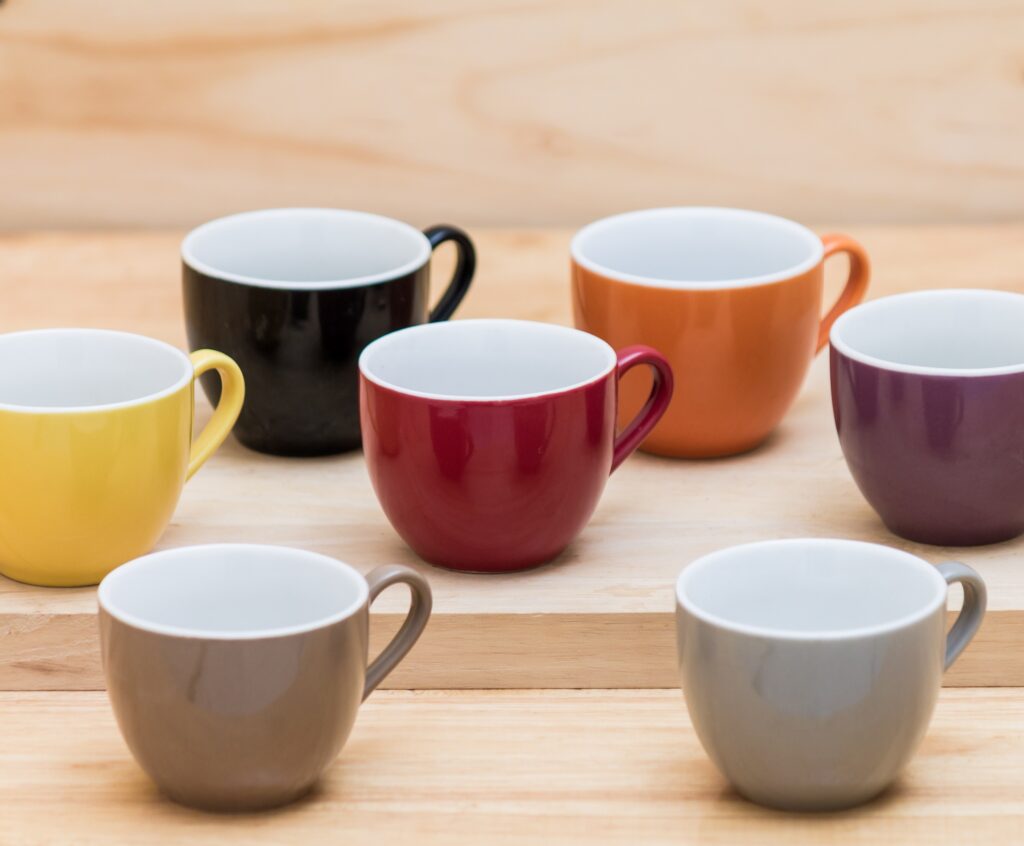 Colorful ceramics cups on the wooden shelf