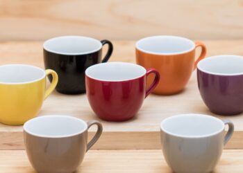 Colorful ceramics cups on the wooden shelf