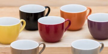 Colorful ceramics cups on the wooden shelf
