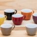 Colorful ceramics cups on the wooden shelf